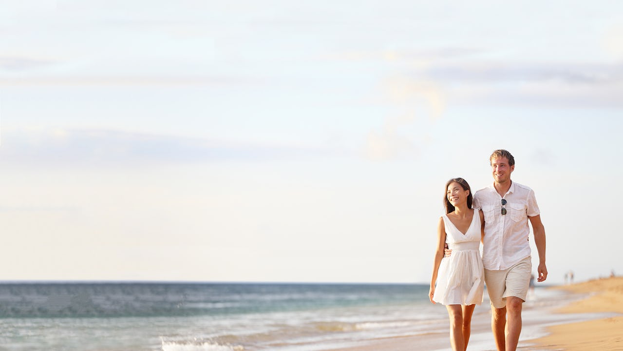 A man and woman walking along the beach smiling