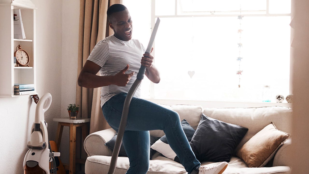 A person rocking out with a vacuum cleaner in their living room