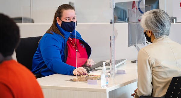 CAA Travel Consultant assisting CAA Member at CAA Store with face masks on