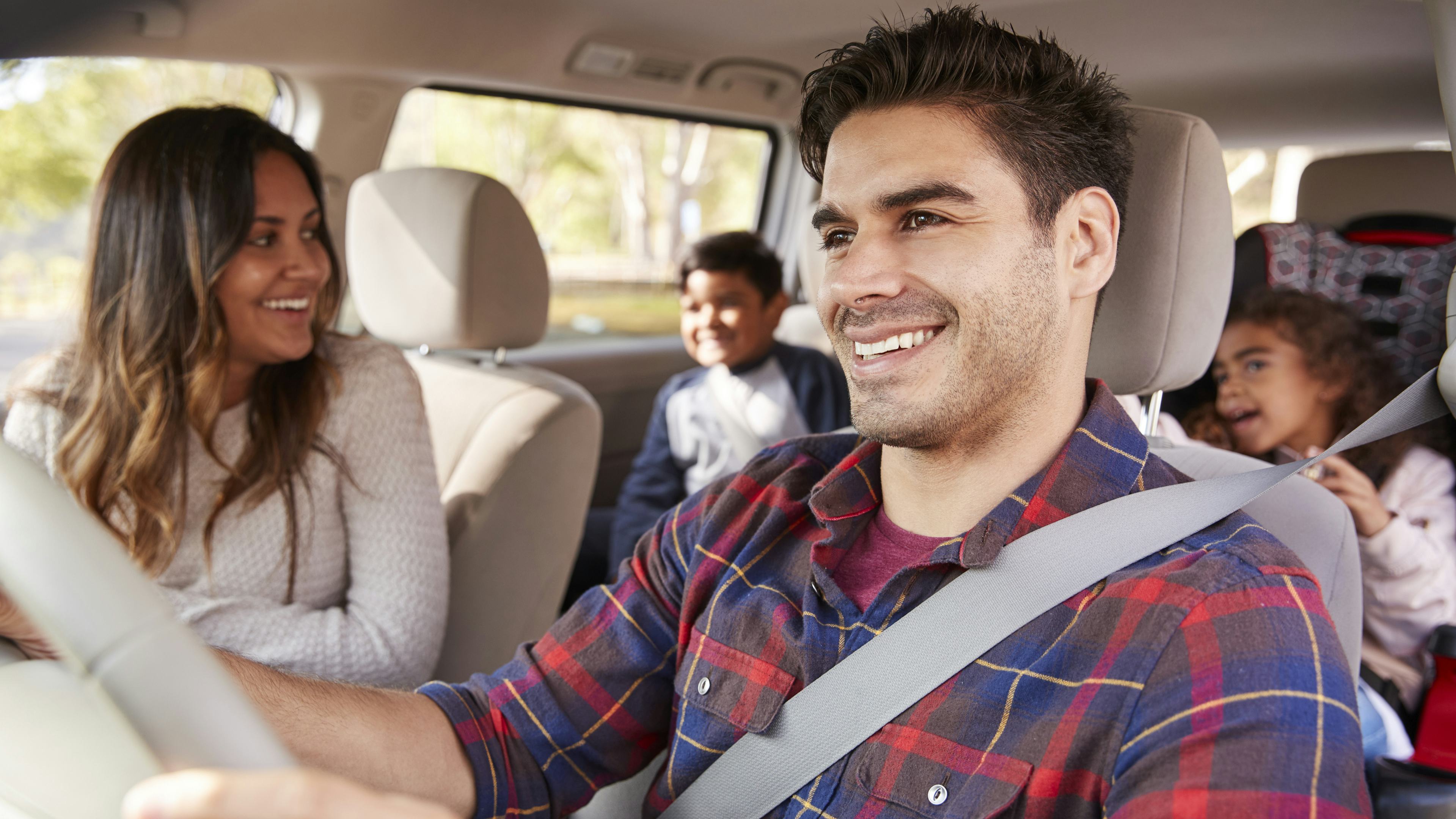 A happy family driving on a road tip with peace of mind coverage from CAA.