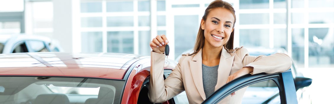 woman smiling next to a new car holding keys 