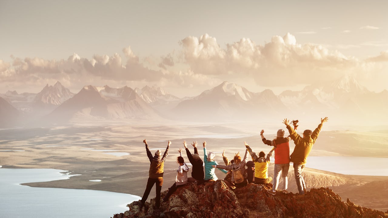 Group on top of mountain with hands in air