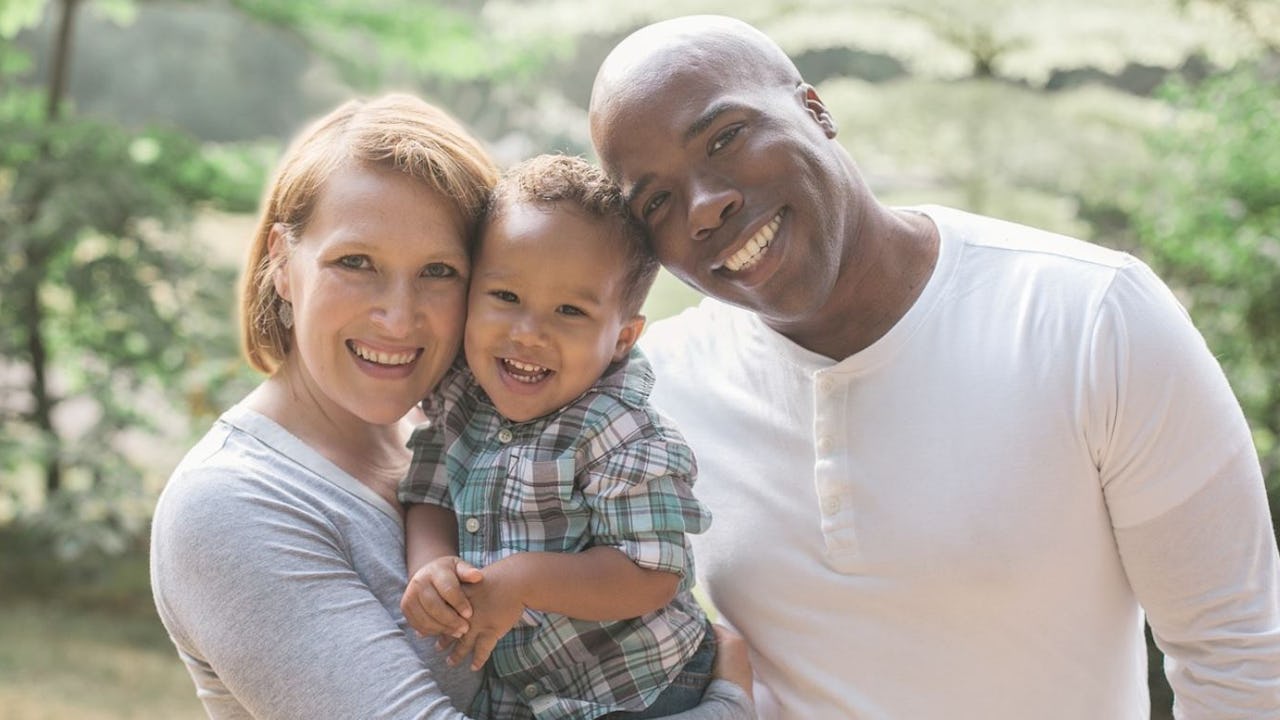 A mixed race family of three smiling at the camera