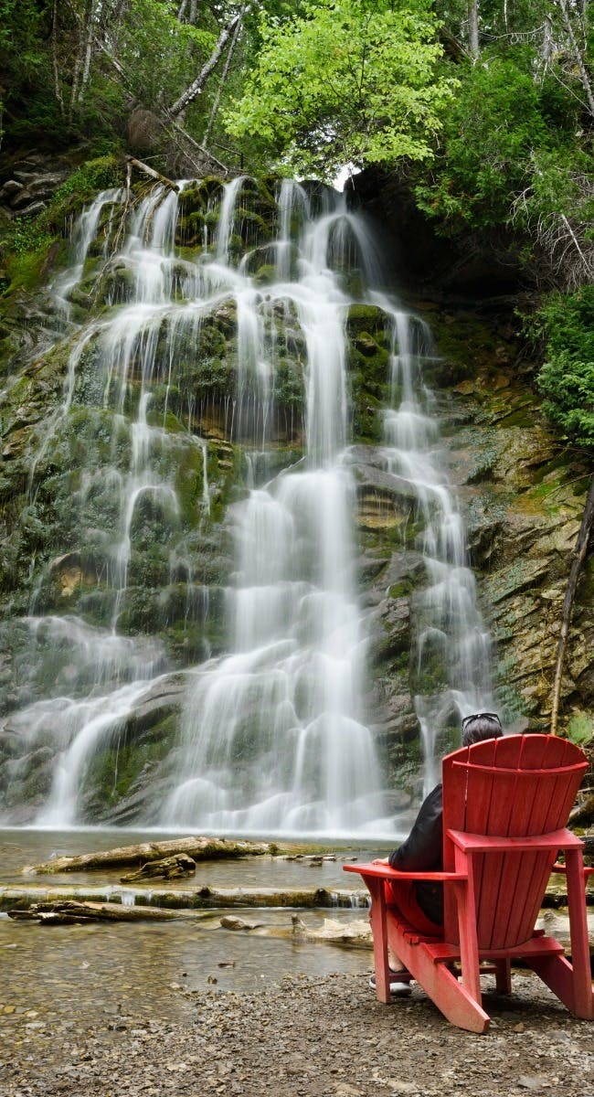 red chair in front of waterfall in Forillon National Park, Quebec