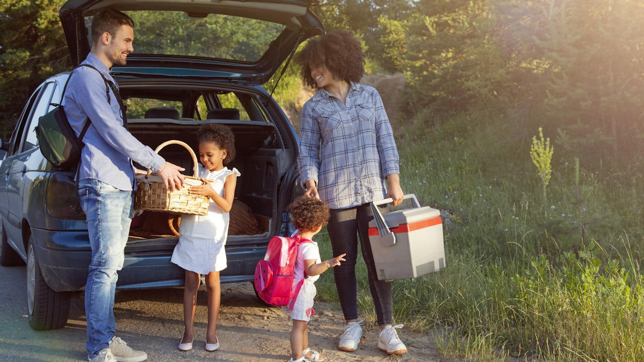 Happy family unloading luggage from the car for summer vacation.