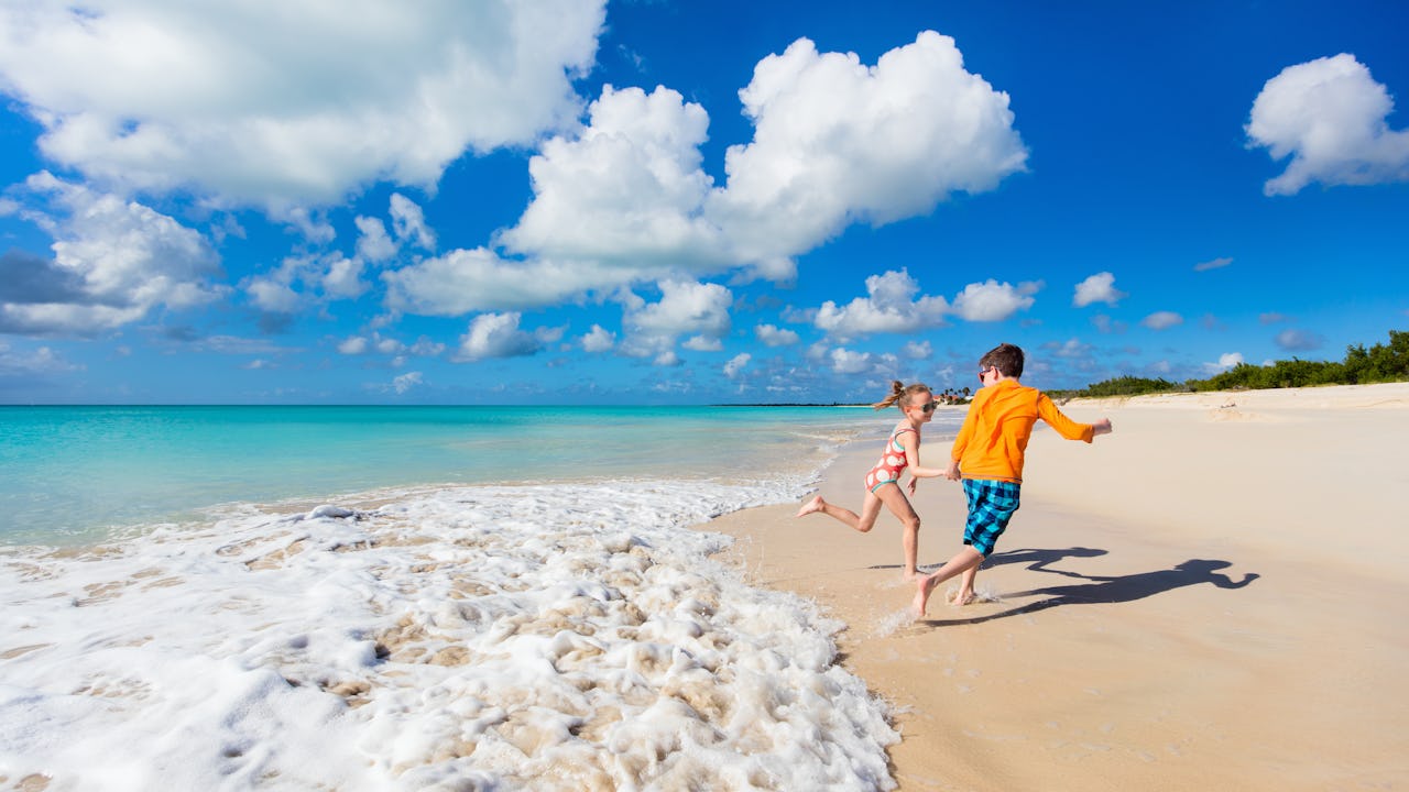 Two kids running on the beach in the Caribbean