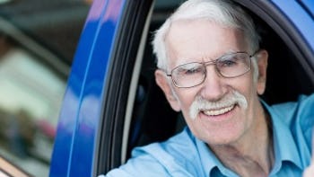 Senior man smiling out car window