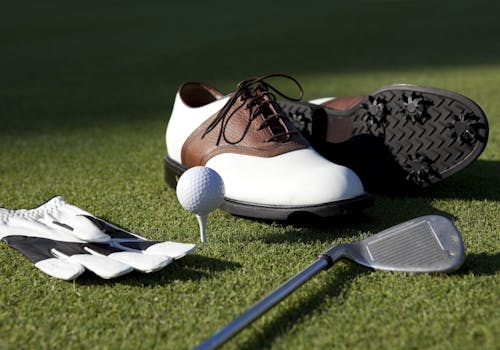 Golf shoes, club, glove and golf ball on a tee