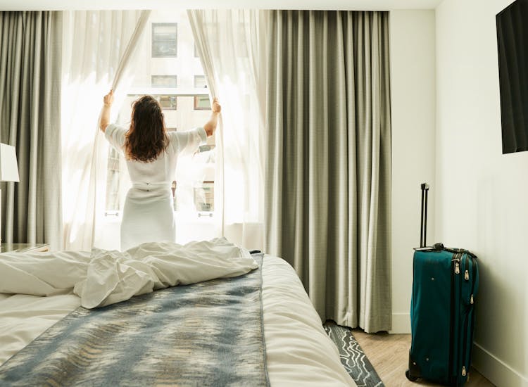 Woman opening curtains at a hotel 