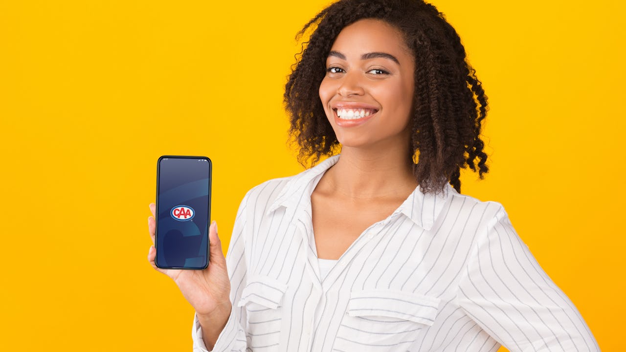Woman holding phone with CAA Mobile App 