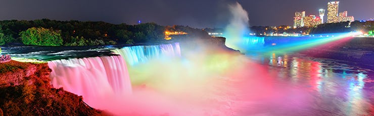 A picture of Niagra Falls  lit up in multiple colours at night