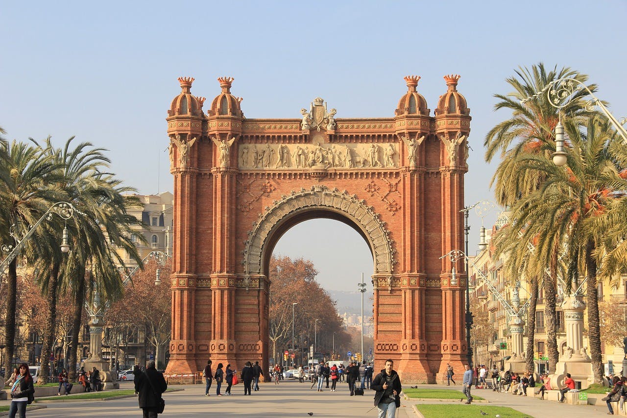 Arc de Triomf in Barcelona, a triumphal arch with intricate details and sculptures, under a clear blue sky.