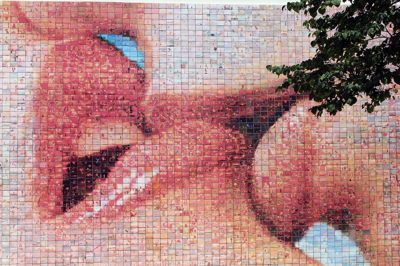 A colorful mural titled "El Beso" depicting a passionate kiss between two individuals.