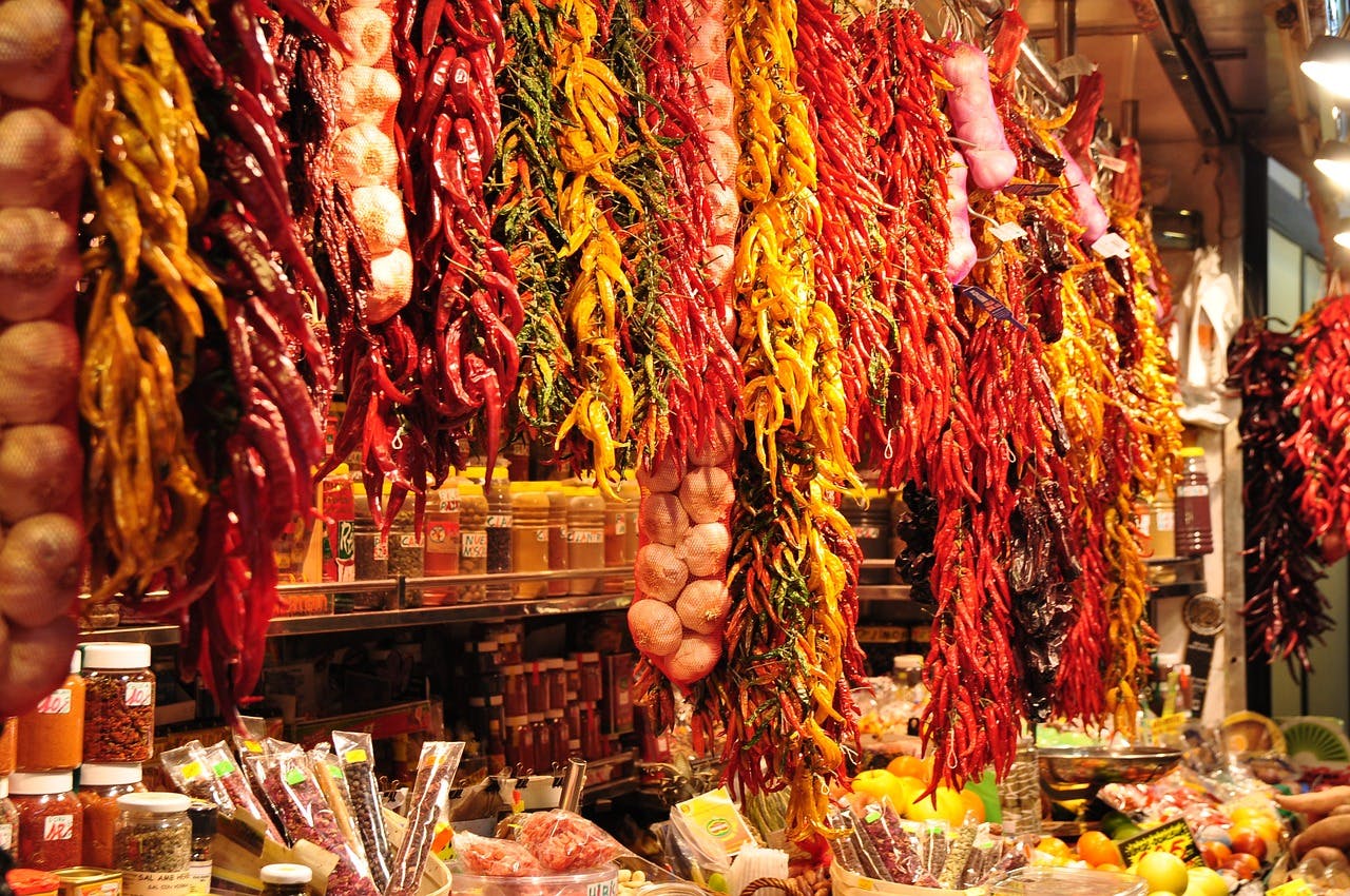 A vibrant market scene at Mercat de la Boqueria, showcasing an array of peppers in various colors and shapes.