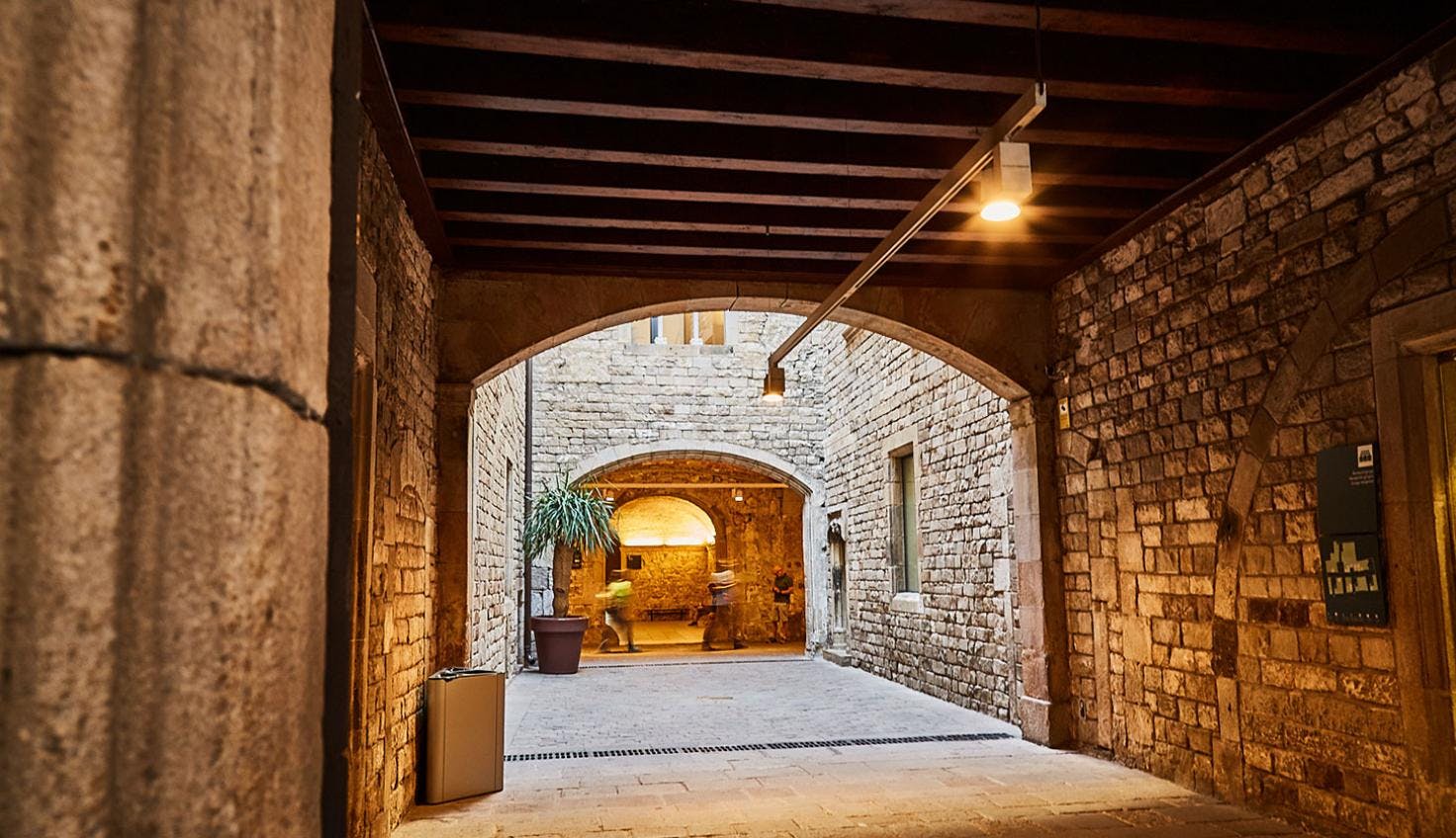 A dimly lit narrow hallway with stone walls, leading to one of Barcelona museums.