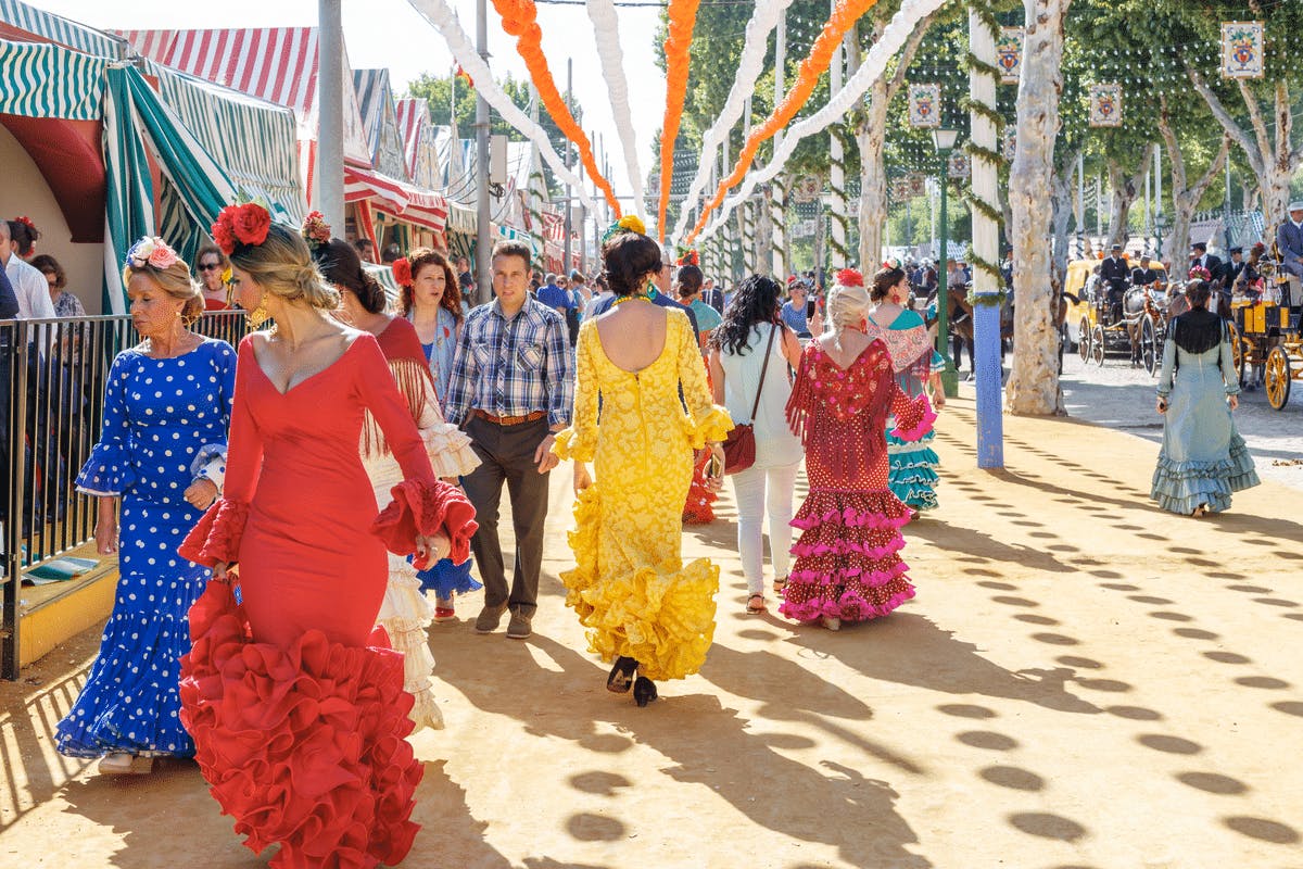 A lively group of women, dressed in bright colours, stroll down the street.