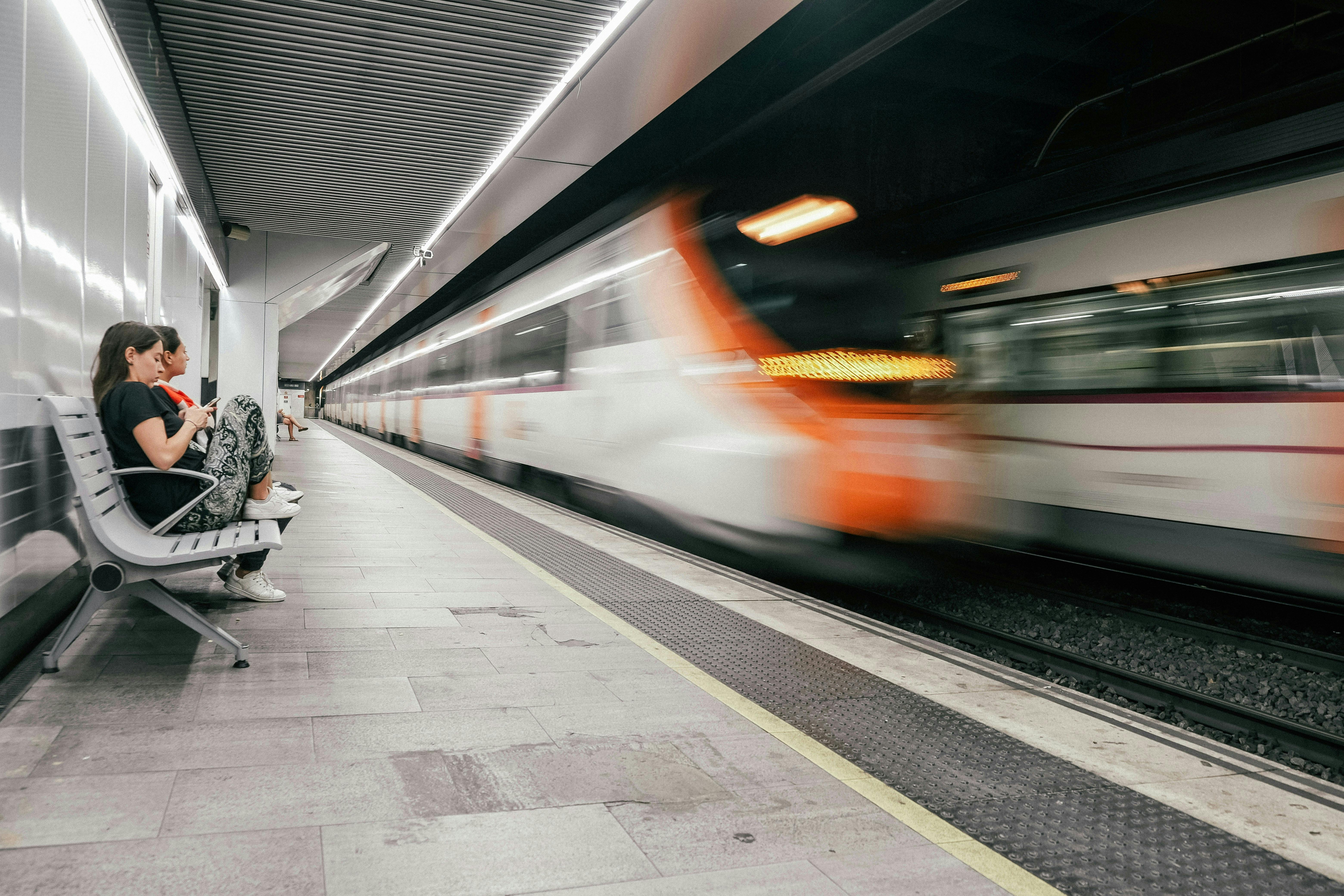 A woman in a train station, surrounded by other customers, anticipating the train service.