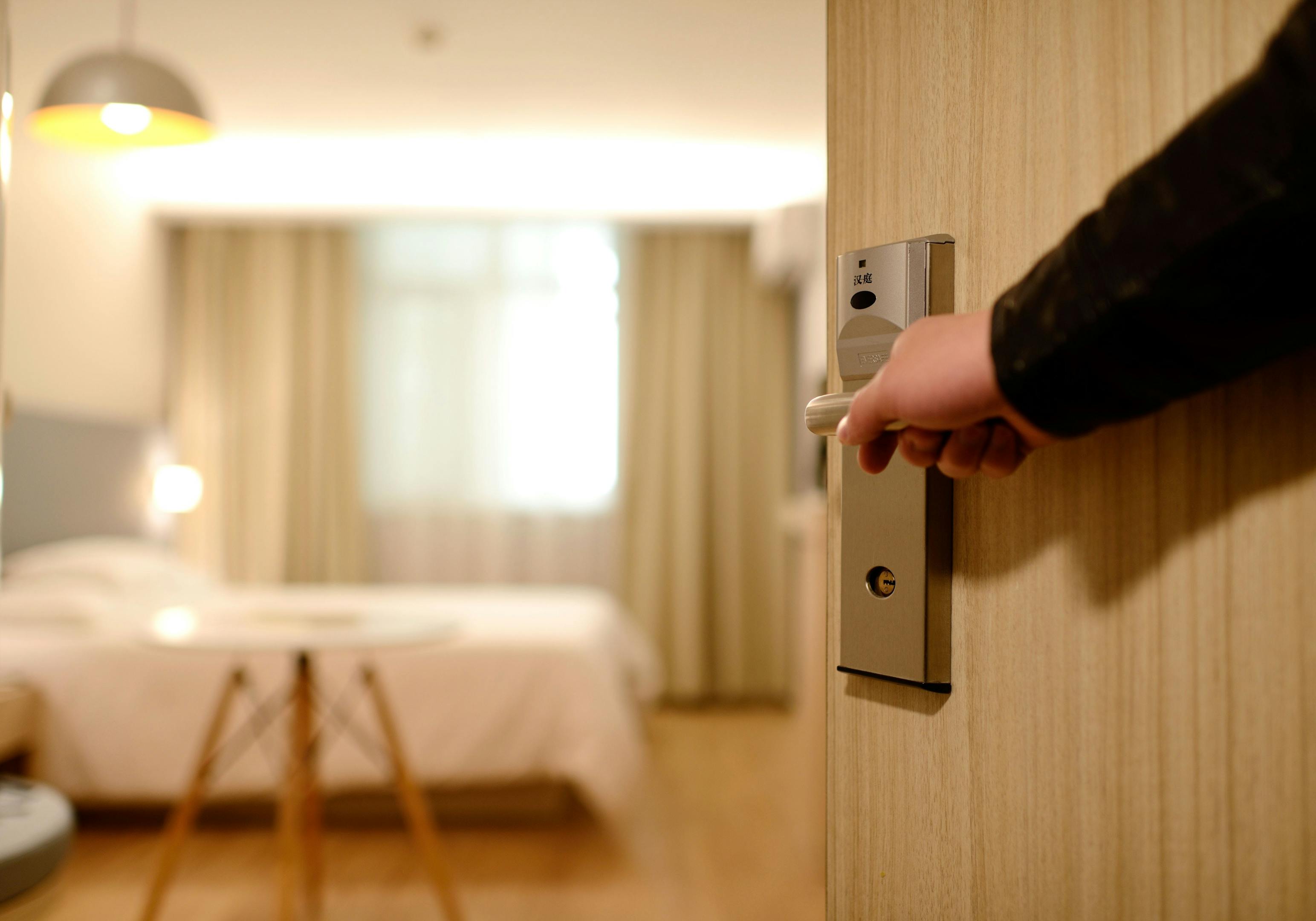 A tired person opening a door to an accommodation room.