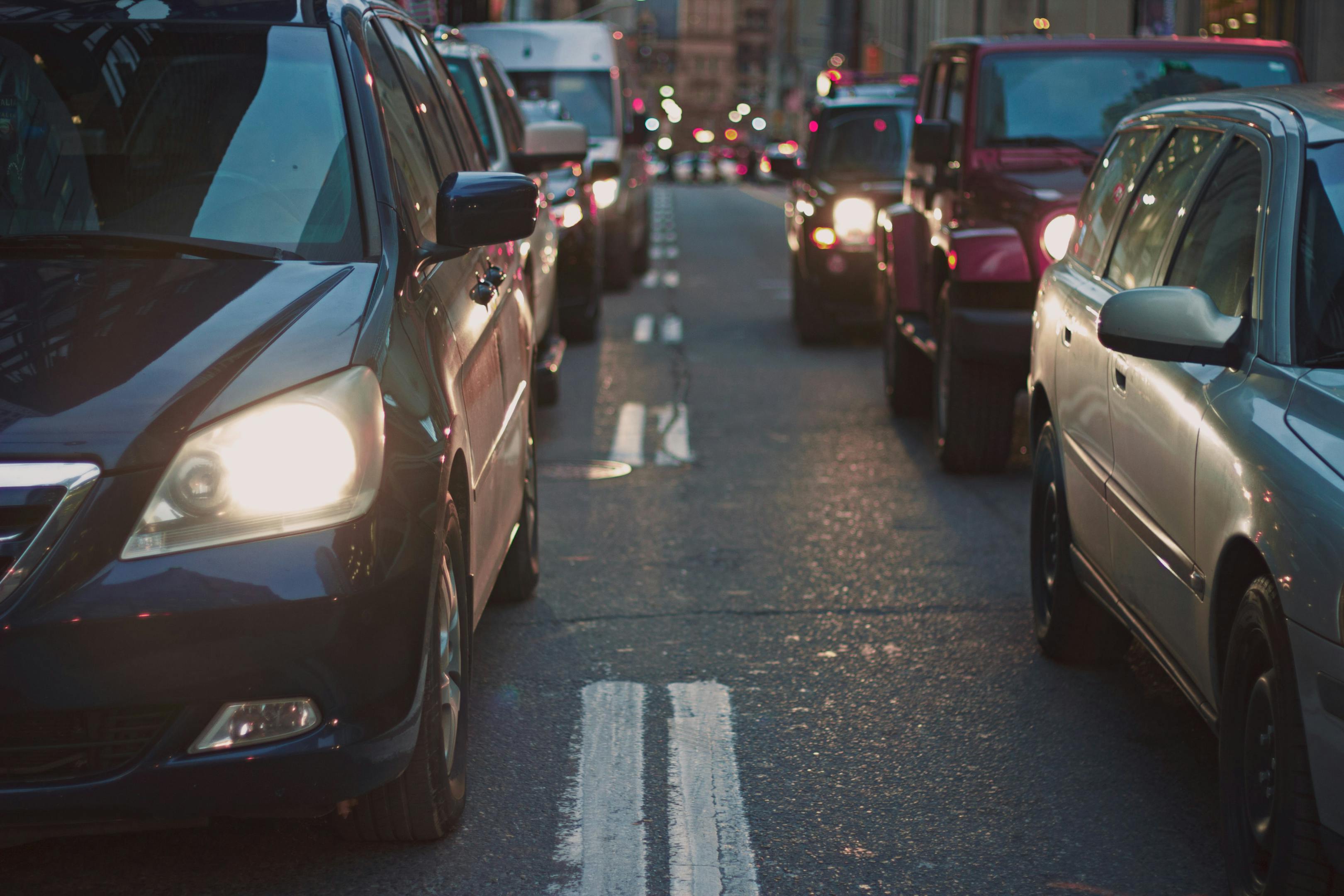 Cars driving down a busy street at night.