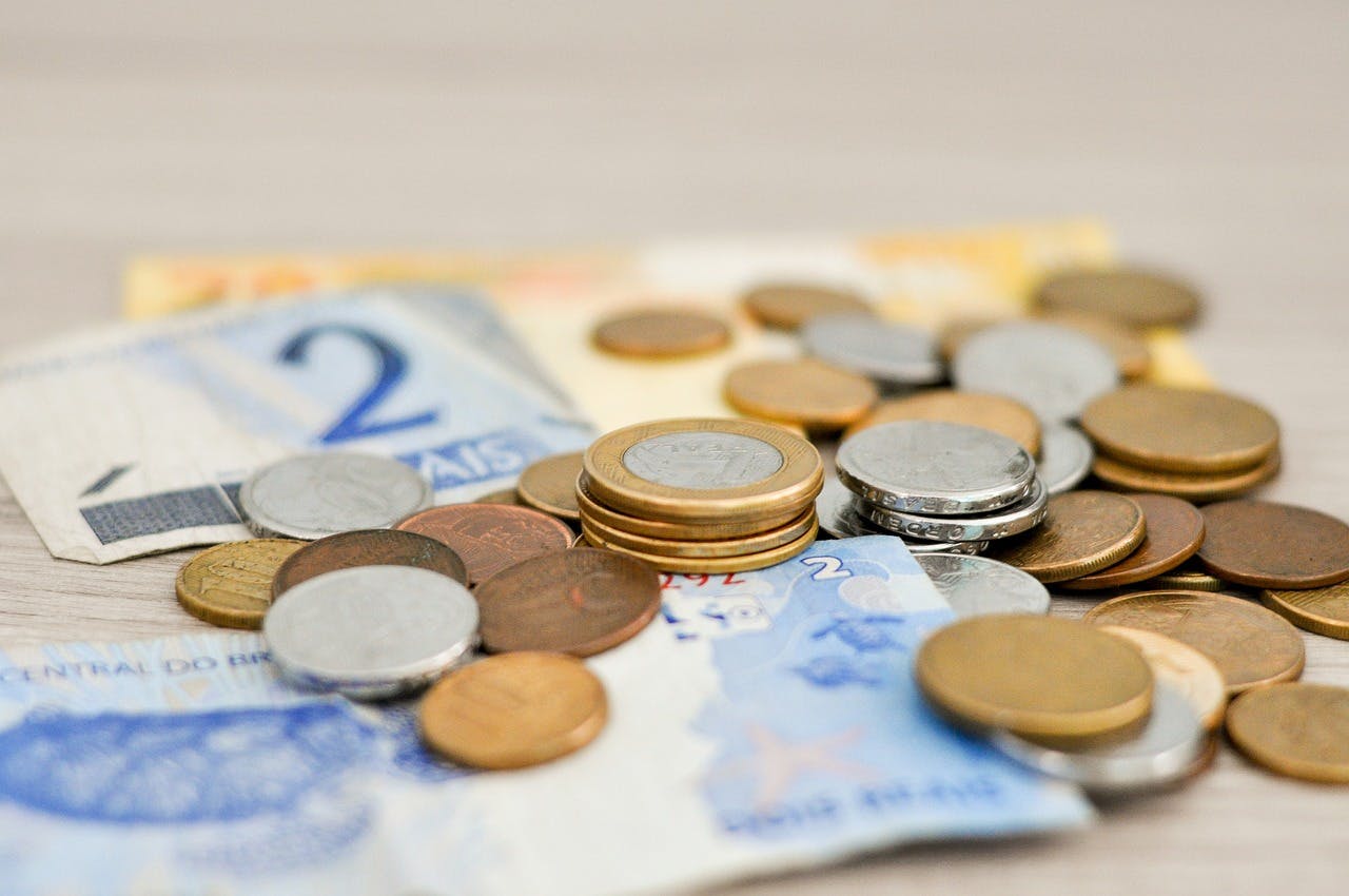 Euro coins and bills neatly arranged on a wooden table, representing a travel budget.