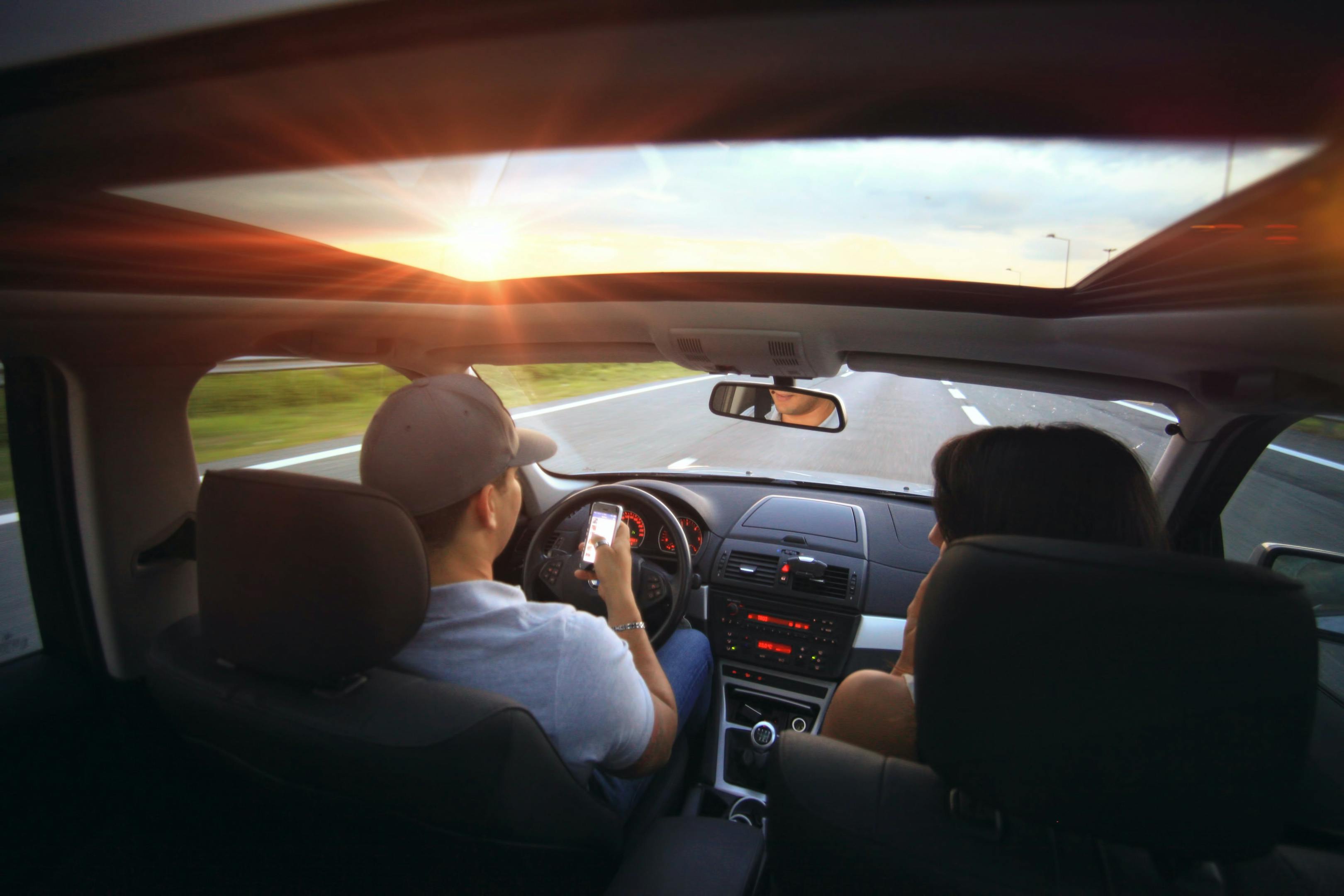 A couple sitting in a car, engaged in conversation and looking out the window.