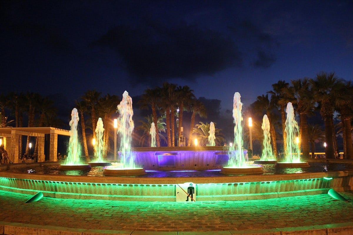 A lovely sight of Salou's Illuminated Fountain glowing in green and blue hues at night.