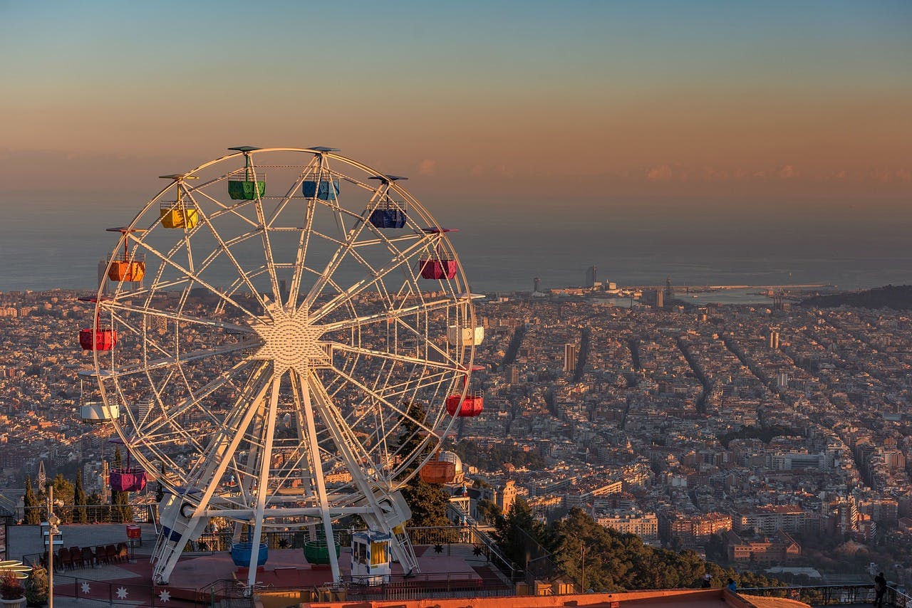 A Ferris wheel stands atop a hill at Tibidabo Amusement Park, providing a thrilling experience for kids in Barcelona.