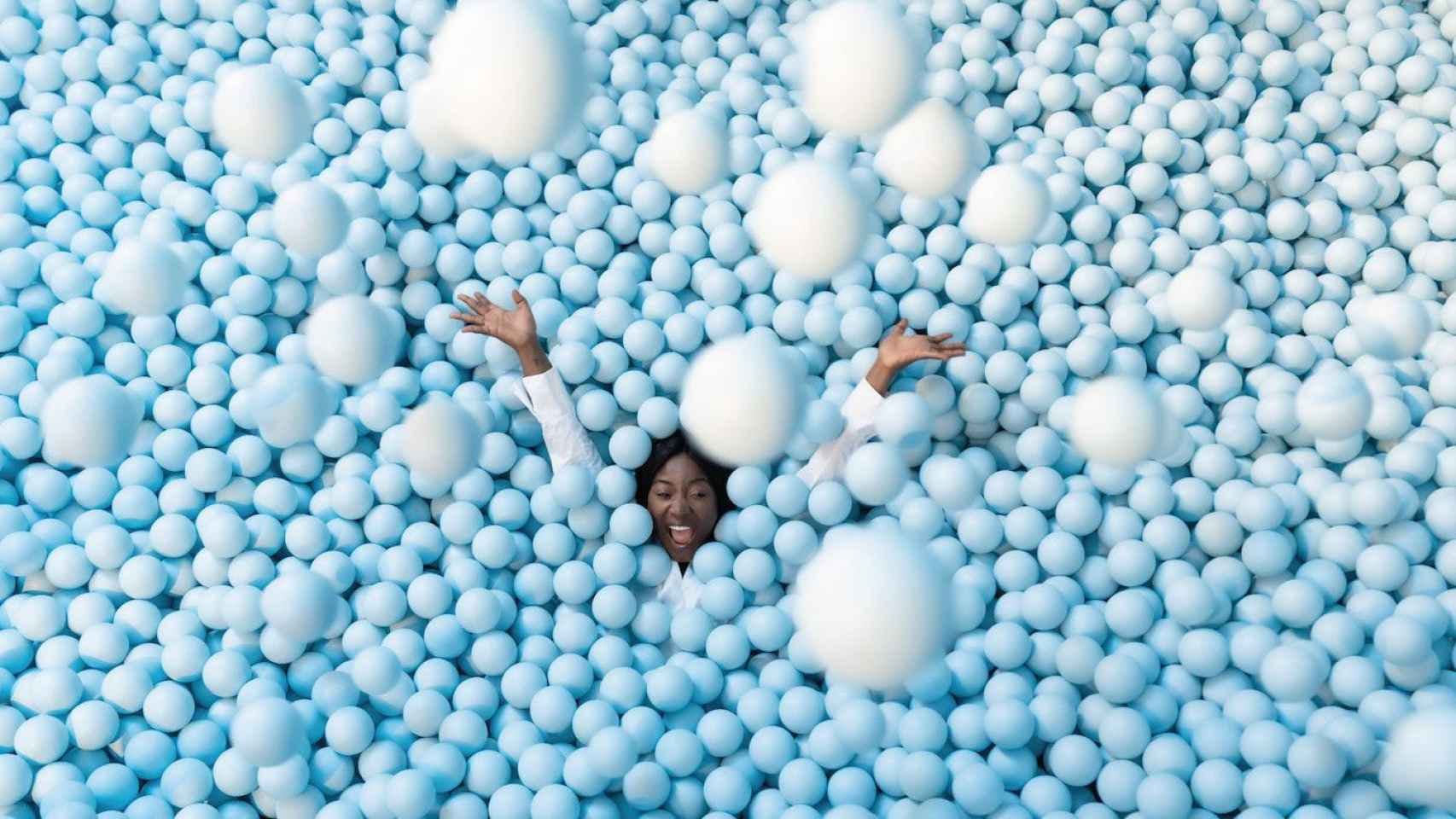 A girl at IKONO Barcelona, surrounded by blue balls, engages in a vibrant and immersive artistic experience.