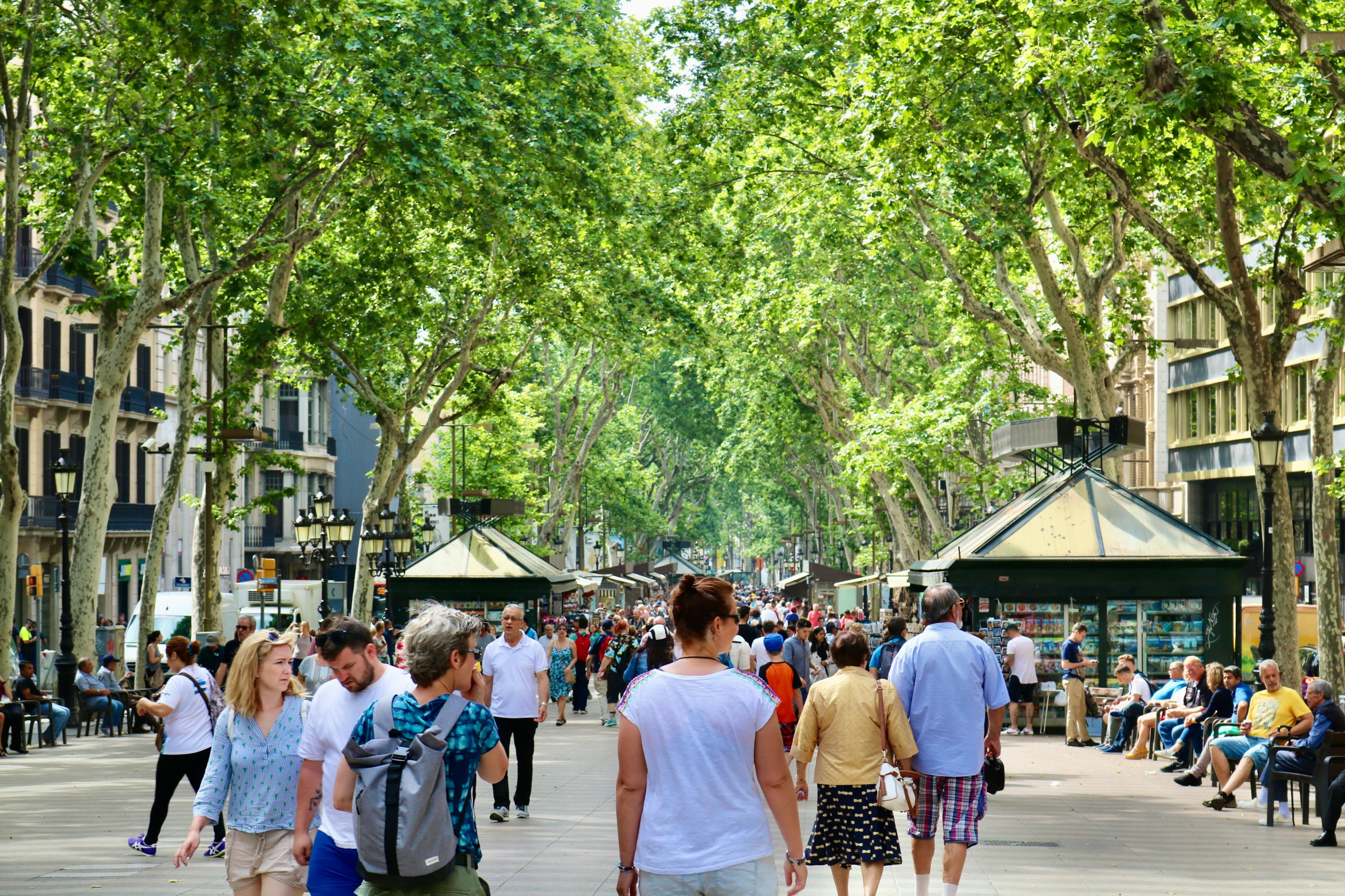 A diverse group of individuals strolling down La Rambla, a bustling street in Barcelona.