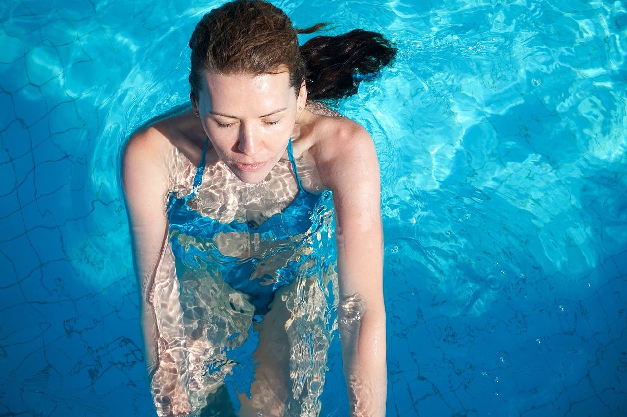 A woman after booking a hotel in a blue bikini enjoying a refreshing swim in a pool.