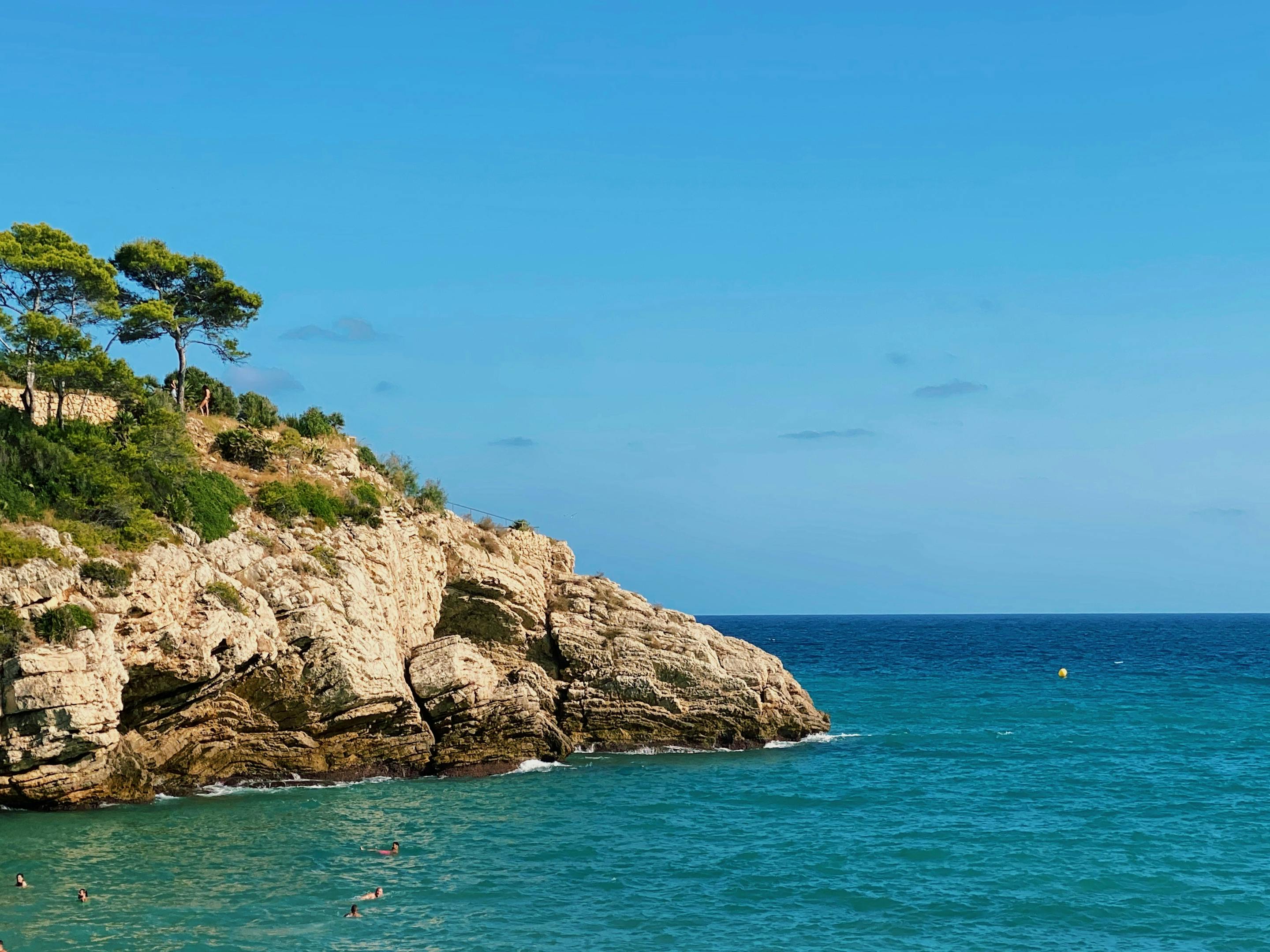 Rocky cliff with trees and a beach in Salou.