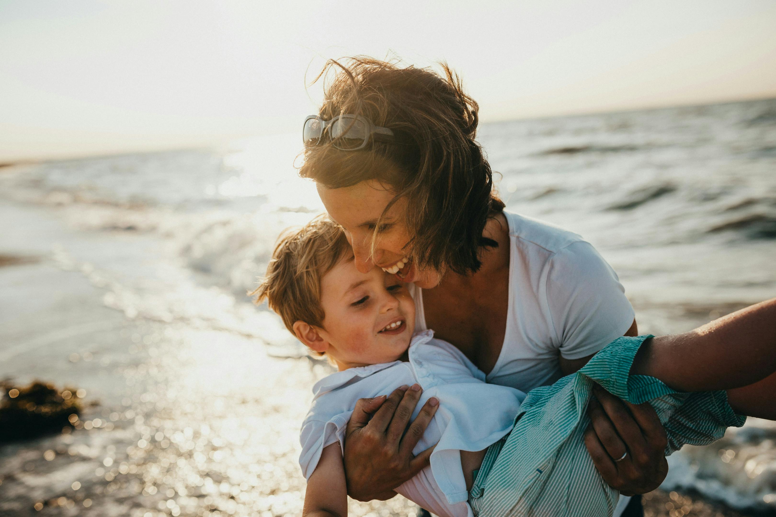 A mother and her son enjoying a sunny day at the beach, creating memories and bonding together.