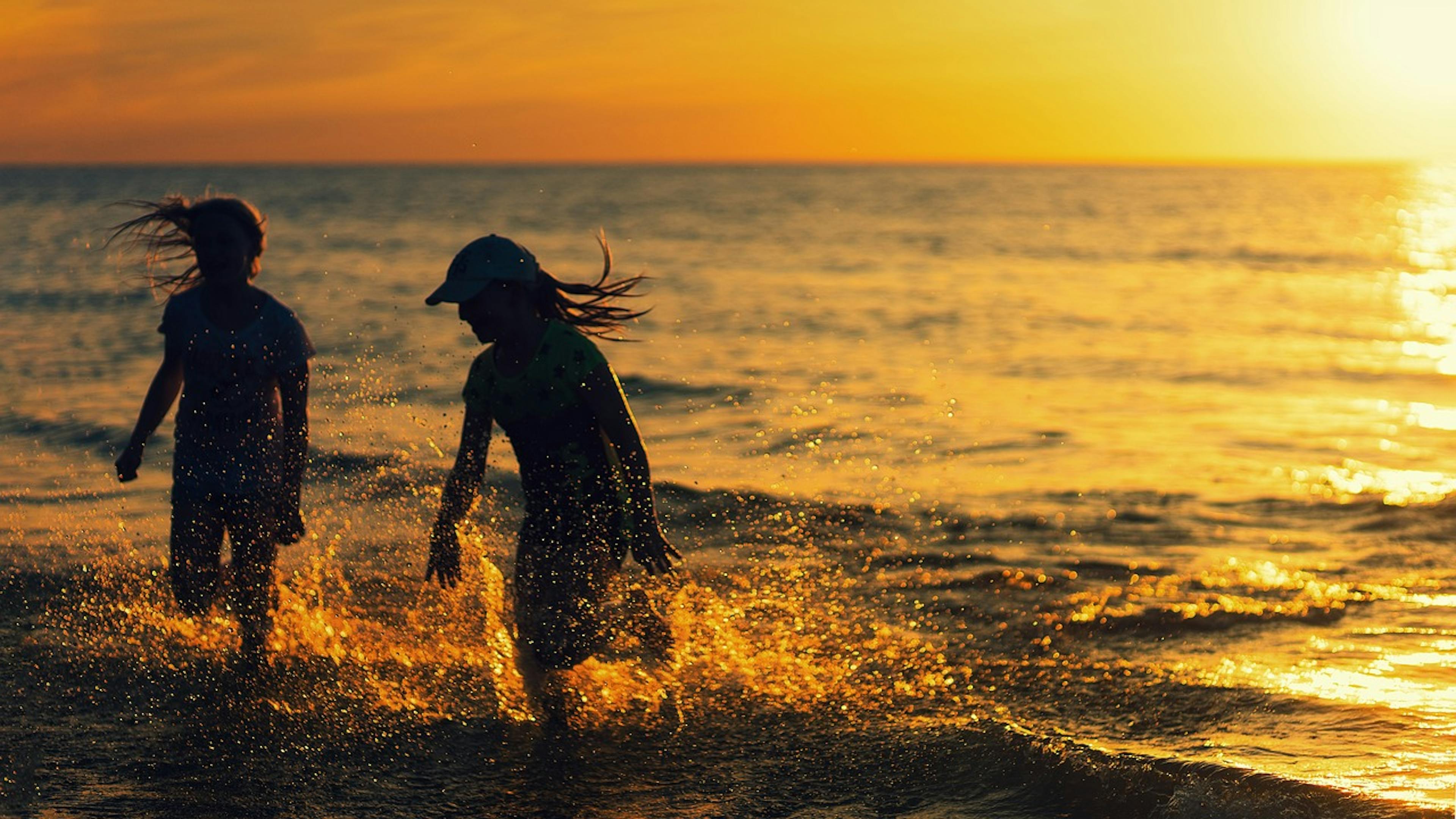 Two people joyfully playing in the ocean at sunset on the beautiful beaches of Salou.