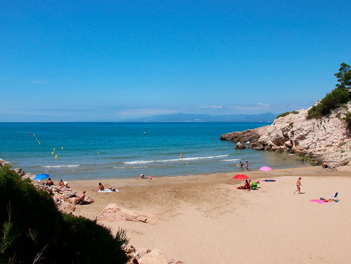 Sandy beach at Fountain Cove, Salou, with people enjoying the sun and sea.