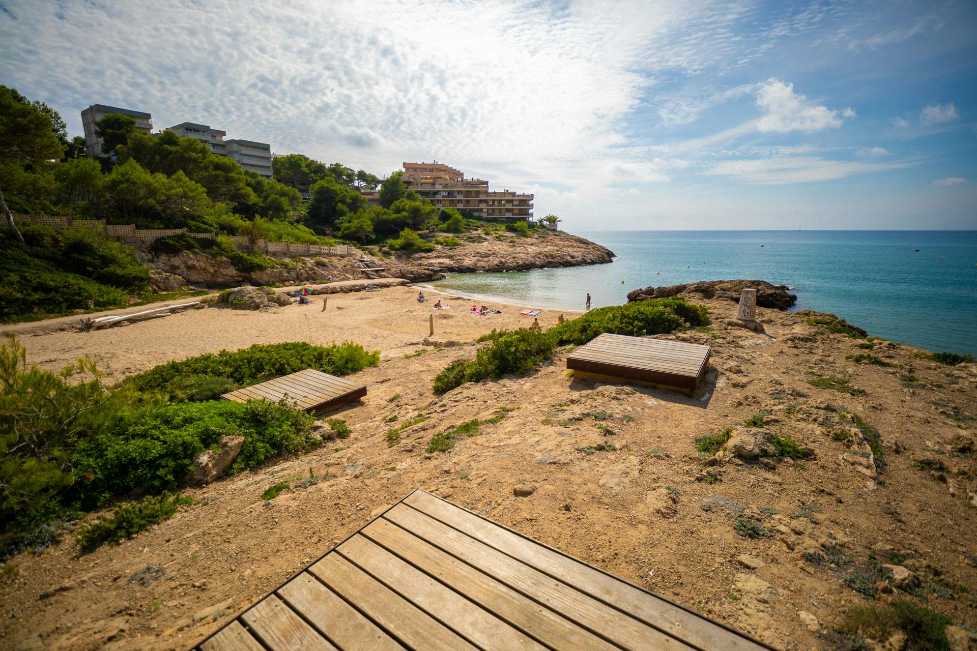 A serene beach at Vineyard Cove, Salou, featuring wooden benches and a breathtaking view of the ocean.