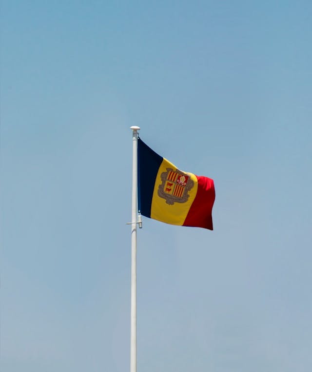 Le drapeau d'Andorre-la-Vieille flotte au vent dans le ciel bleu.