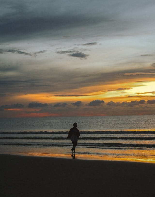 Une personne profitant du coucher de soleil sur la plage.