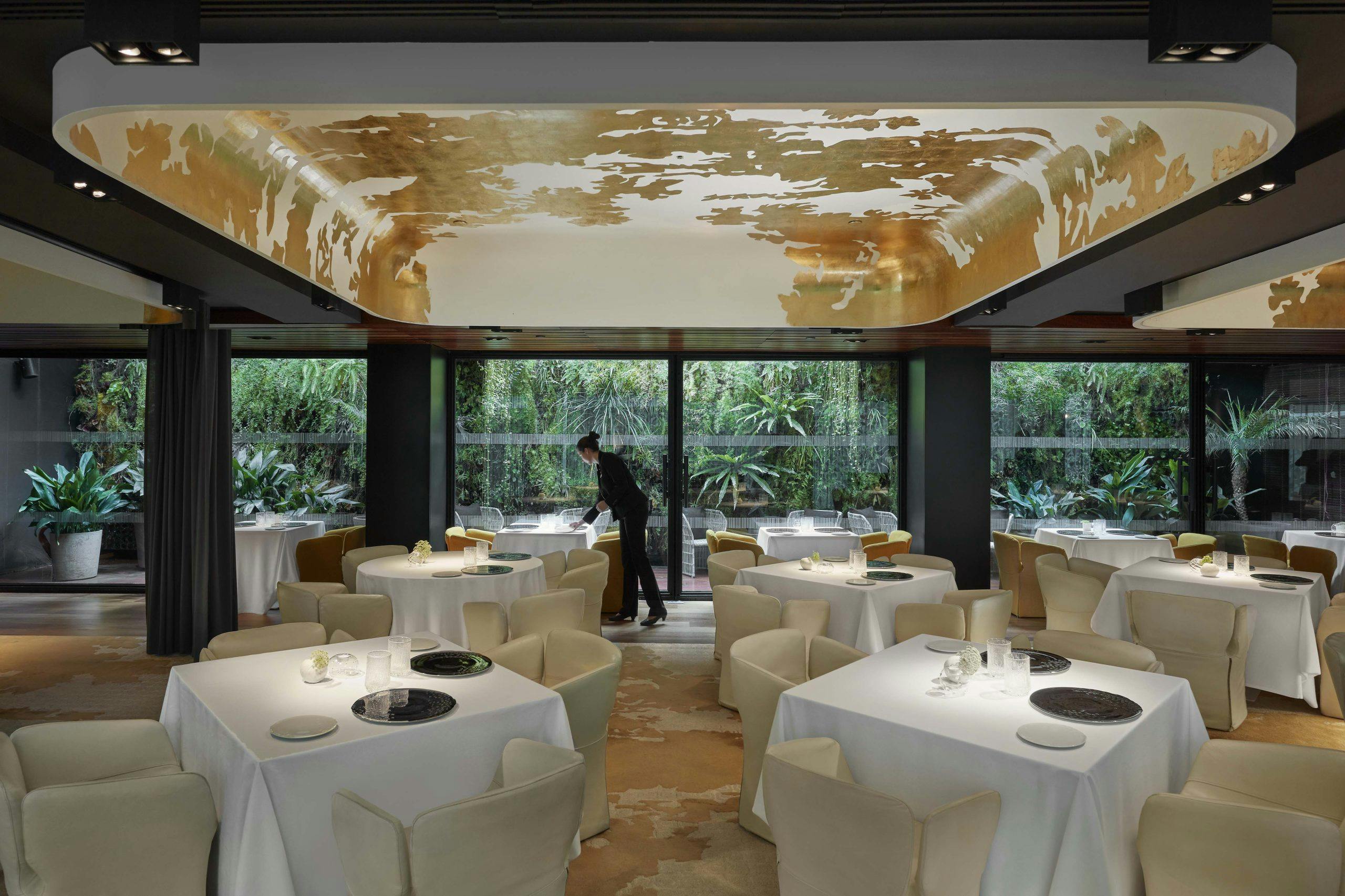 A Two Michelin Stars restaurant, Moments, showcases tables and chairs in front of expansive windows.