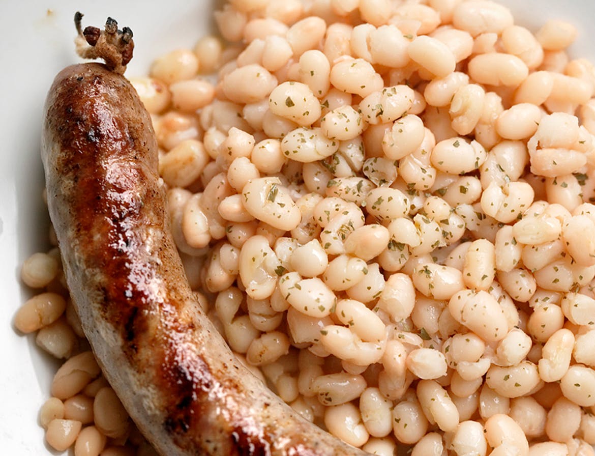 A plate of Botifarra amb Mongetes, a Catalan dish, featuring beans and a sausage.