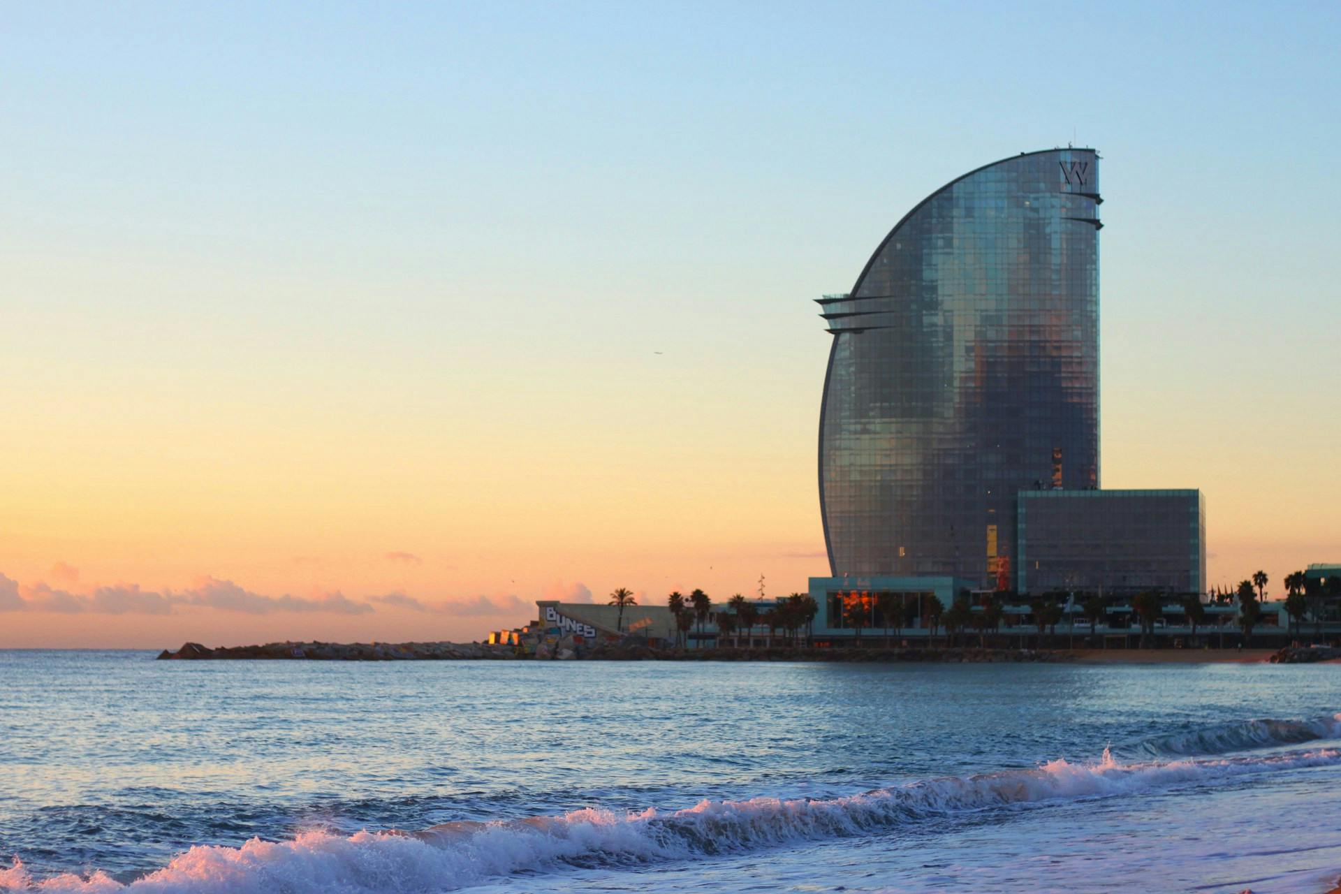 Aerial view of Barcelona's iconic W Hotel under a clear blue sky.