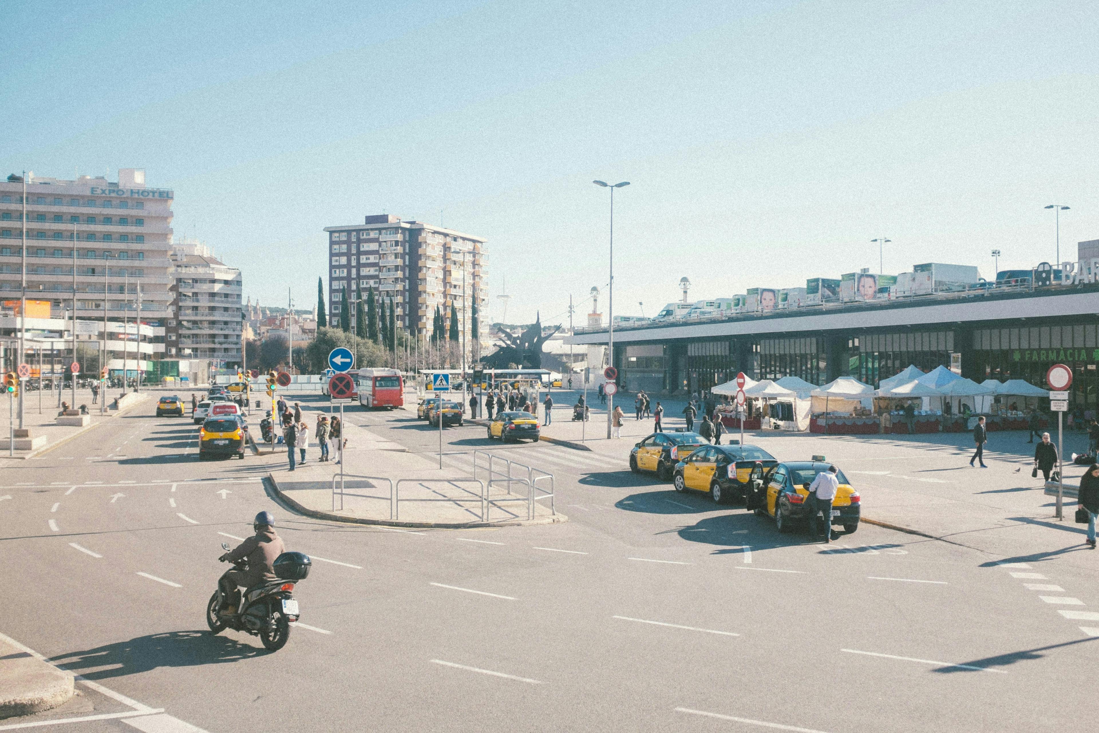 A bustling Barcelona street filled with people and cars during rush hour.