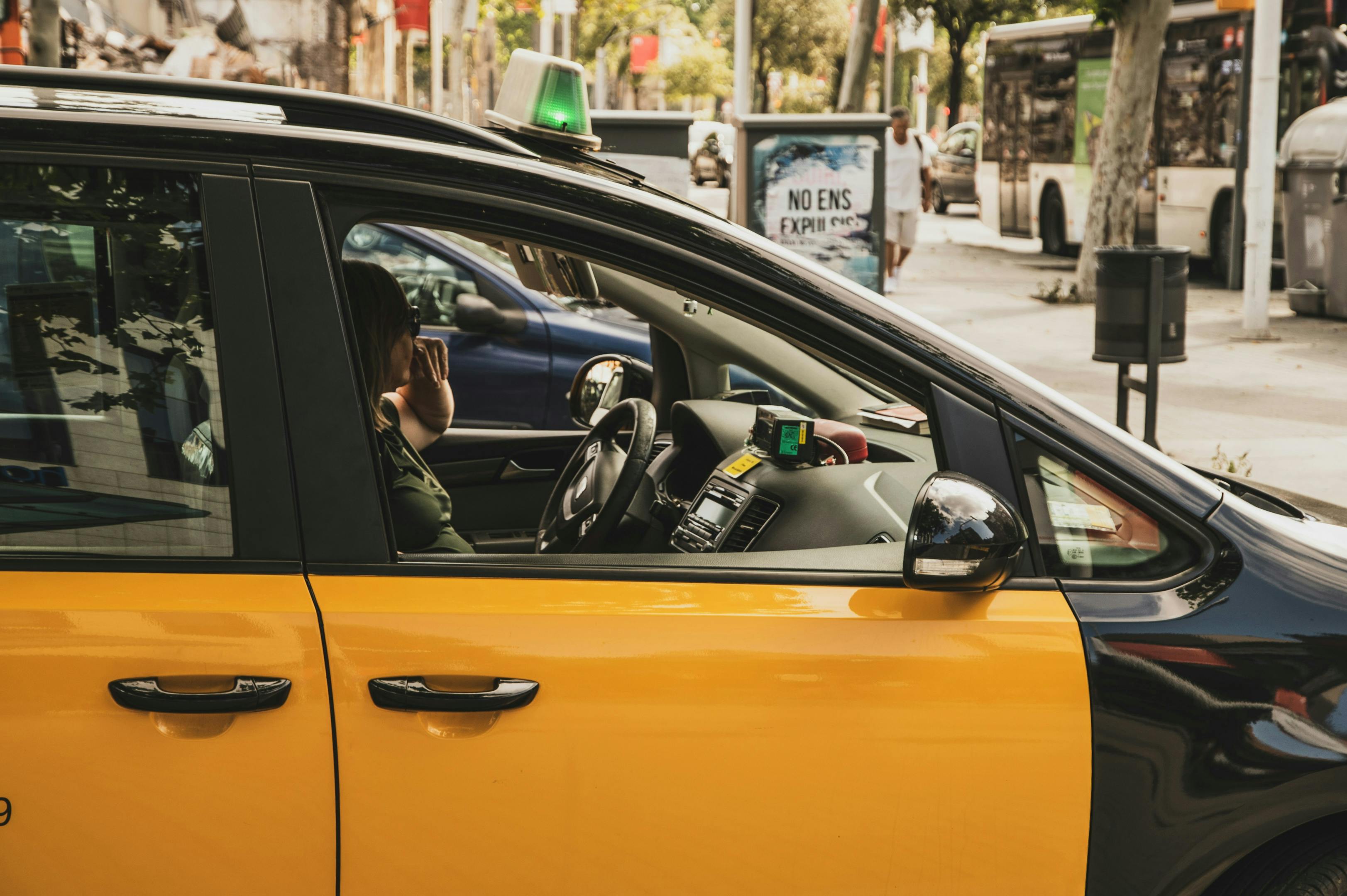 A taxi from Barcelona with a woman as a driver, driving along the street.