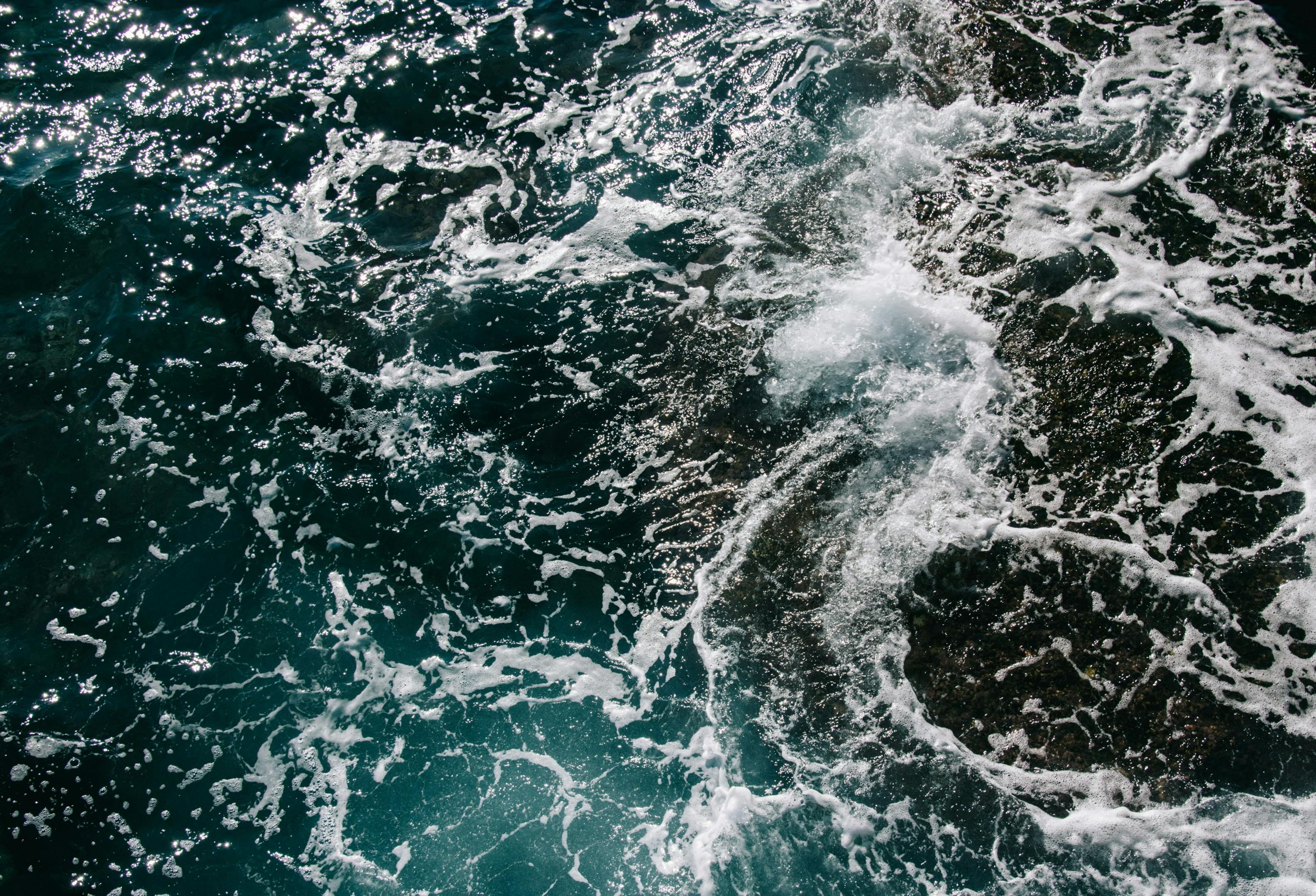 An aerial view of the ocean with waves crashing against the shore.