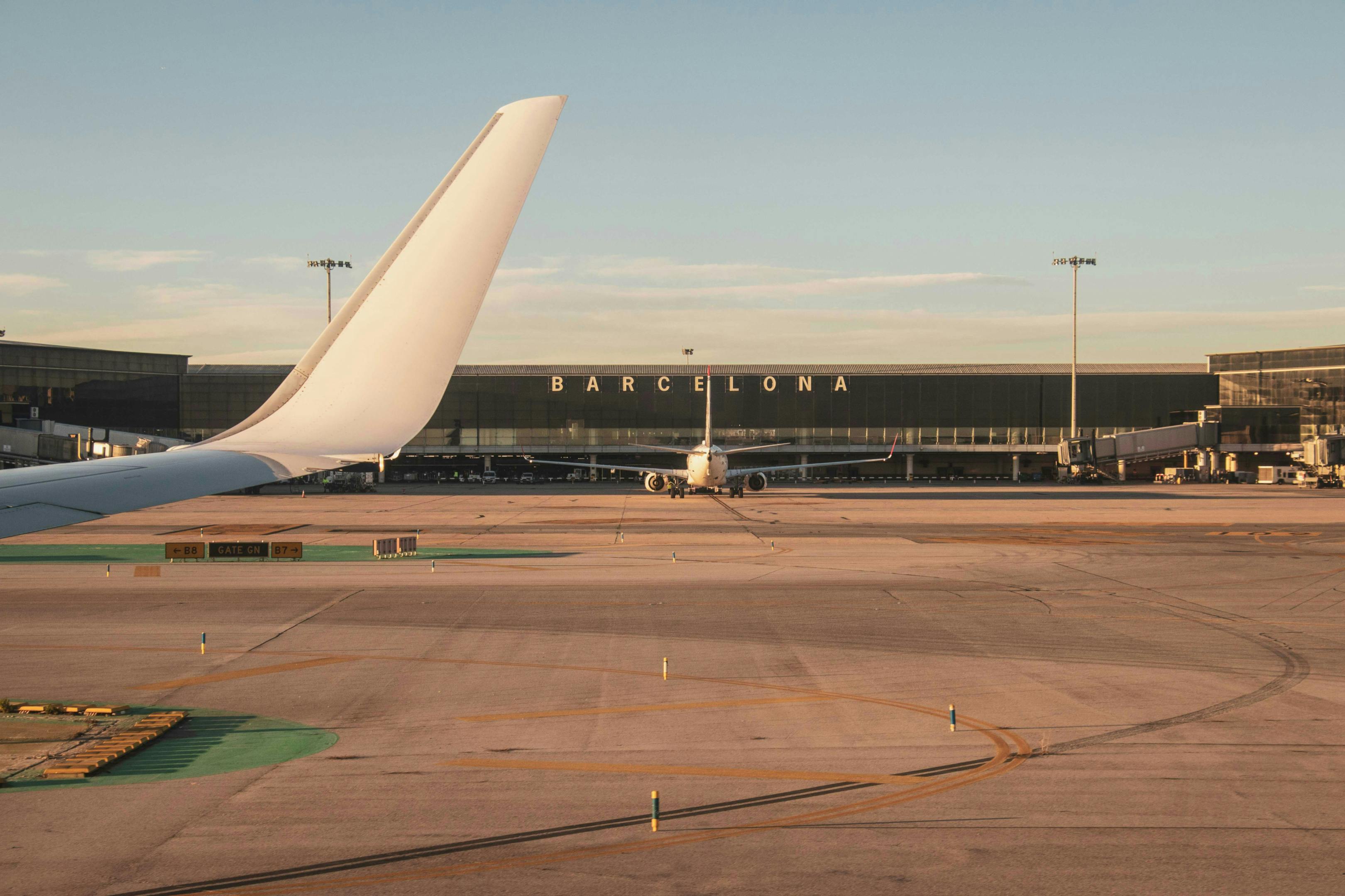 Barcelona Airport: A modern airport terminal with bustling crowds, check-in counters, and airplanes on the tarmac.