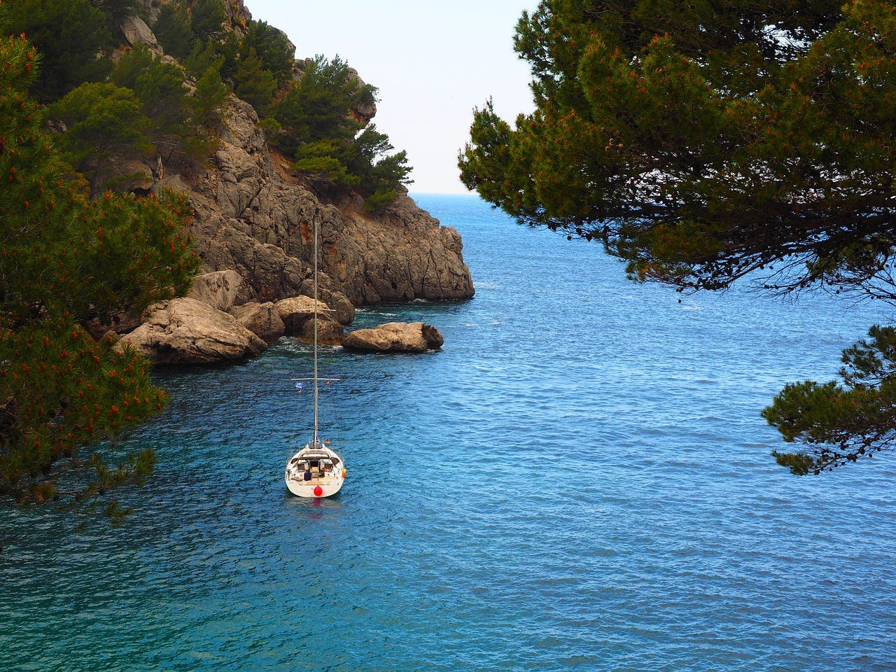 A boat gently floats in the water near the rocky shore of Sa Calobra, Mallorca