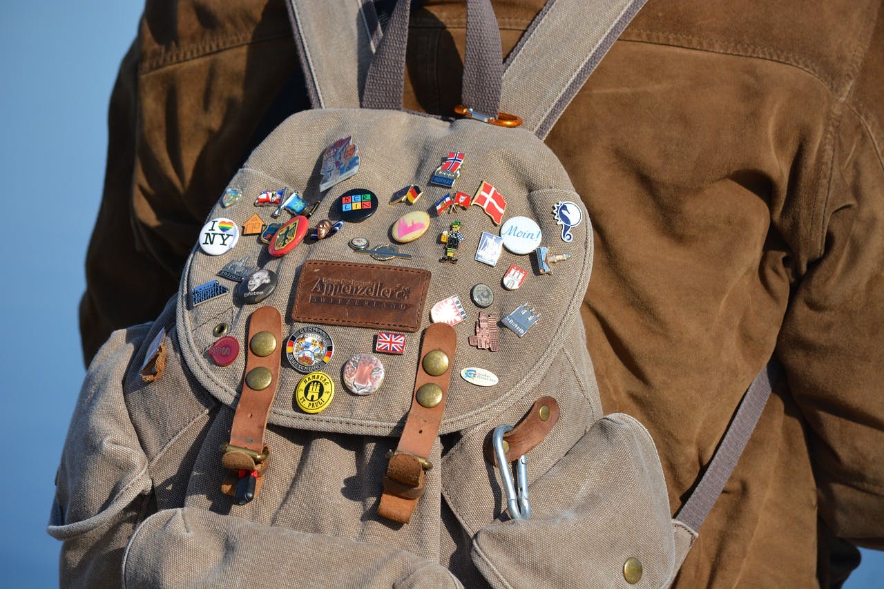 A man with a backpack covered in pins and badges, ready for a day trip in Barcelona, Spain.