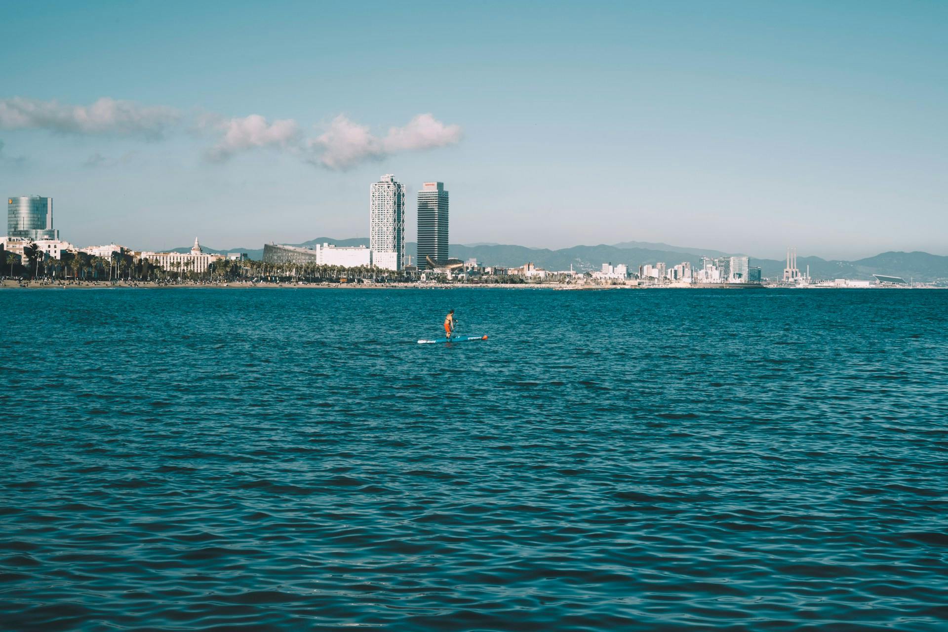 A person on a paddle board in the ocean at La Barceloneta, Barcelona's beachfront neighborhood.