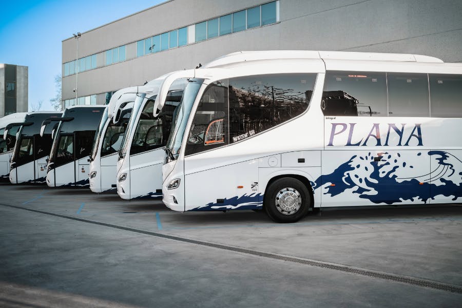 A line of Barcelona buses from Bus Plana parked in a lot. 