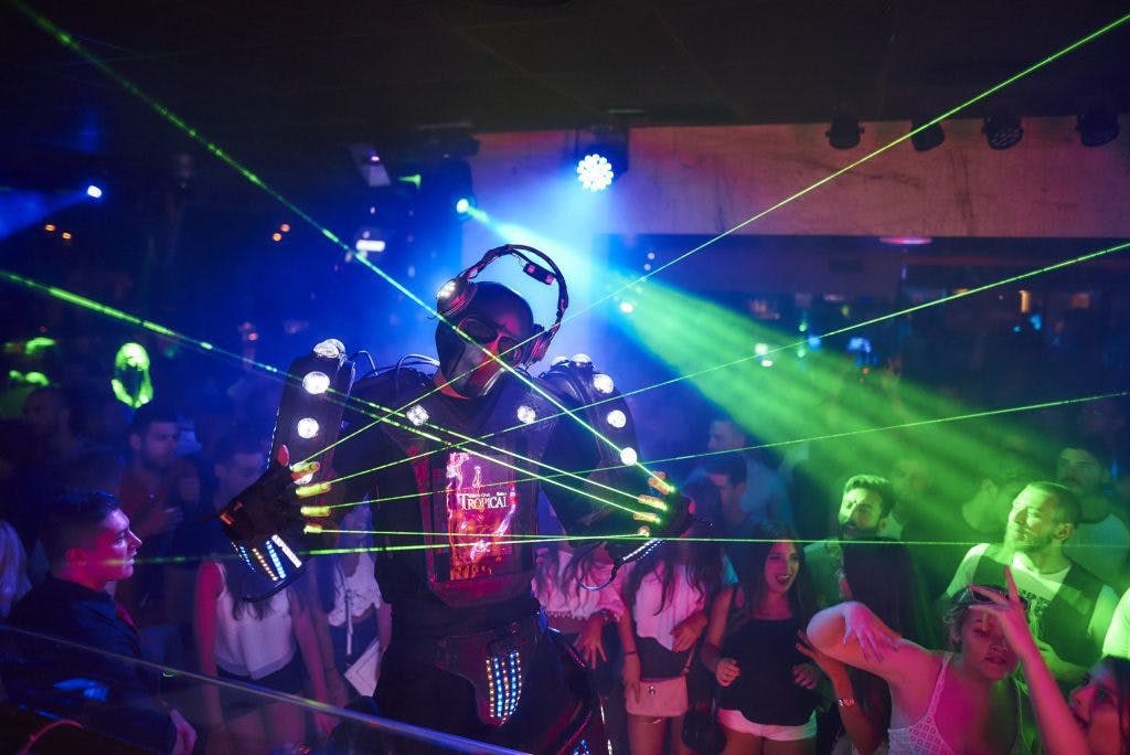 A man in a costume with green laser lights at a night party in Tropical Salou.