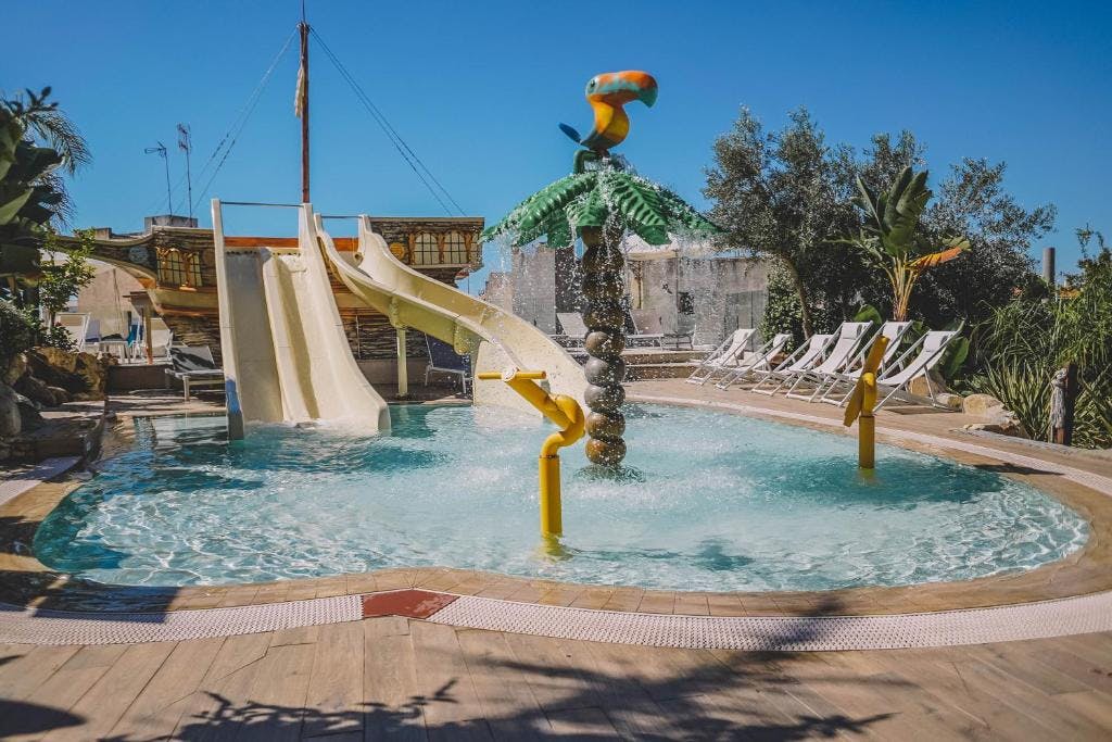 Family-friendly water park featuring a slide and palm tree, situated at a hotel in Lloret de Mar.